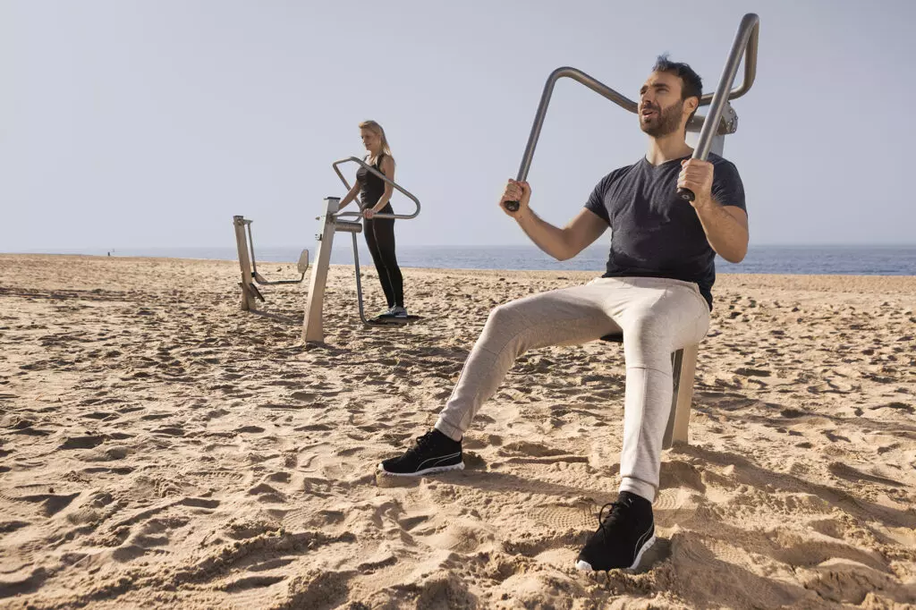 Fitnesstoestellen op het strand met sporters